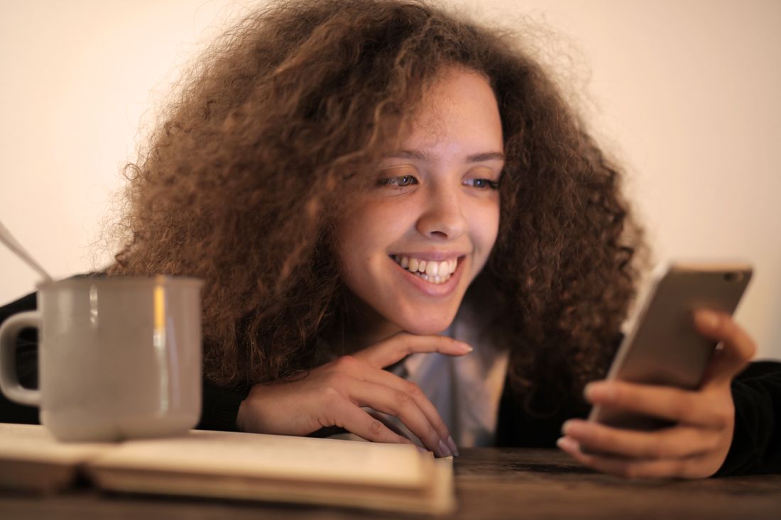 Woman smiling as she reads a message on her phone