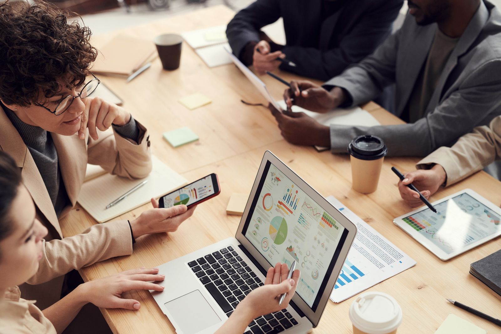 A team around a table reviewing store analytics on a laptop, phones and tablets