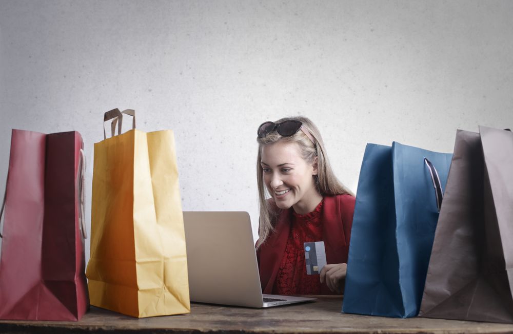 Colorful shopping bags next to a woman shopping online
