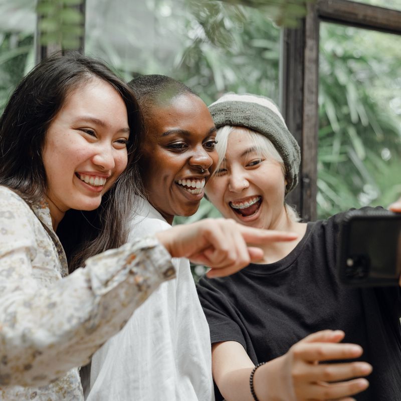 Three friends laughing together while looking at a phone