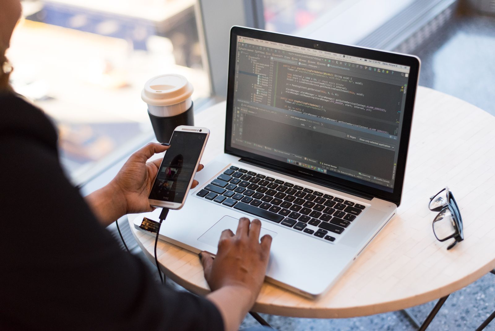 Hands on a laptop showing code, phone beside it